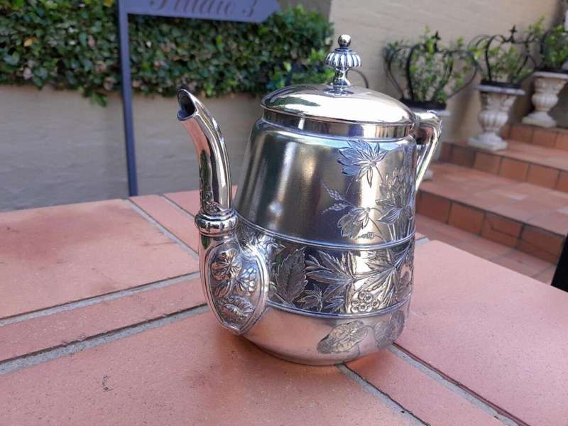 A Silver-Plated Tea Pot With Floral Designs