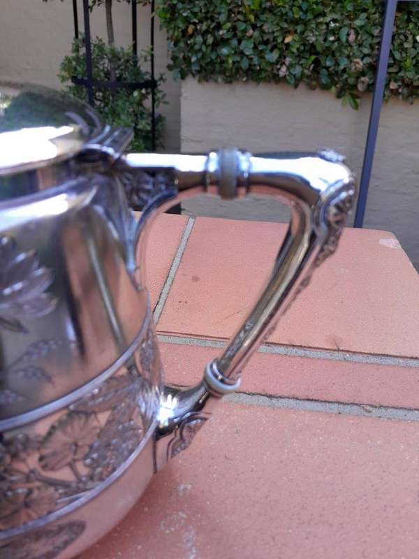 A Silver-Plated Tea Pot With Floral Designs