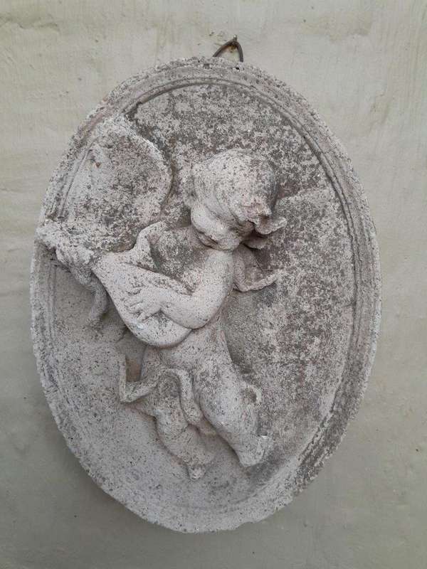 A Concrete Relief Oval Sculpture Of An Ornate Cherub Plaque