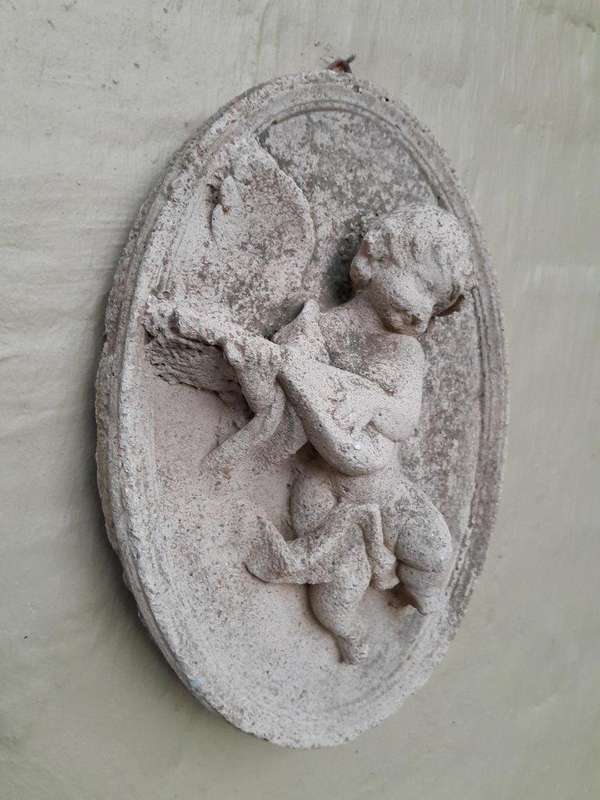 A Concrete Relief Oval Sculpture Of An Ornate Cherub Plaque