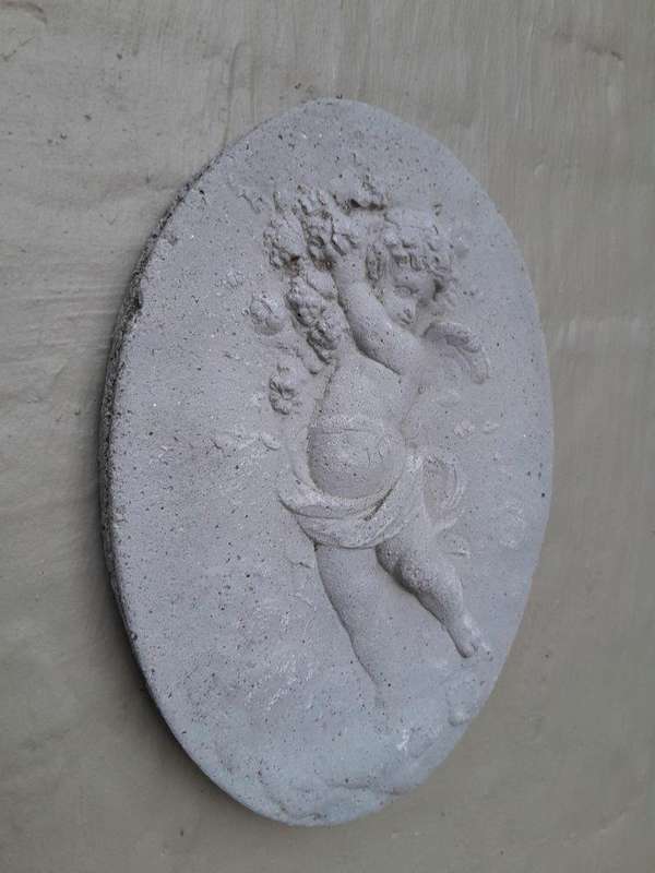 A Concrete Relief Oval Sculpture Of An Ornate Cherub Plaque