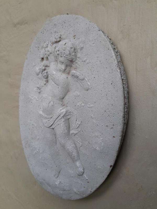 A Concrete Relief Oval Sculpture Of An Ornate Cherub Plaque