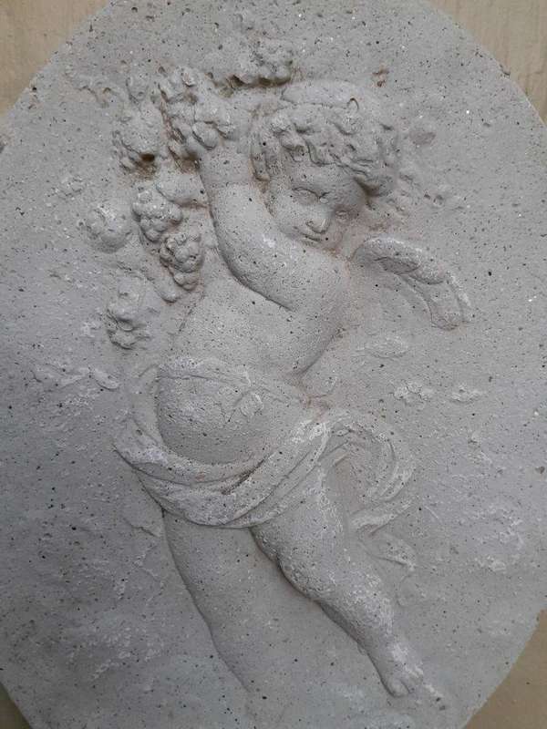 A Concrete Relief Oval Sculpture Of An Ornate Cherub Plaque