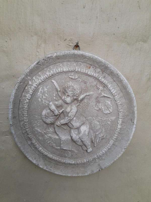 A Concrete Relief Round Sculpture Of An Ornate Cherub Plaque