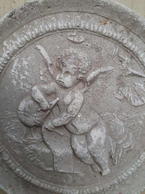 A Concrete Relief Round Sculpture Of An Ornate Cherub Plaque