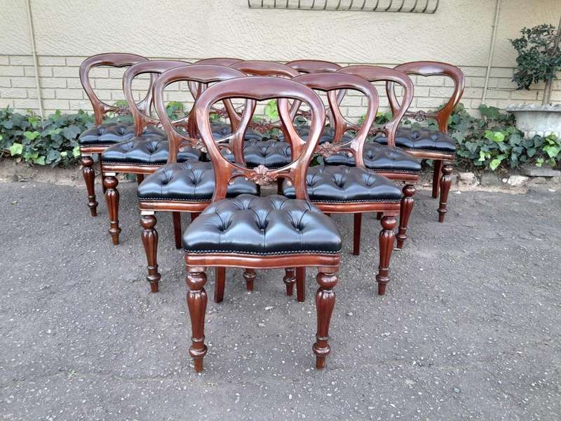 A 20th Century Set of Ten Teak Wood Bustle Back Chairs Upholstered in Deep Buttoned Leather