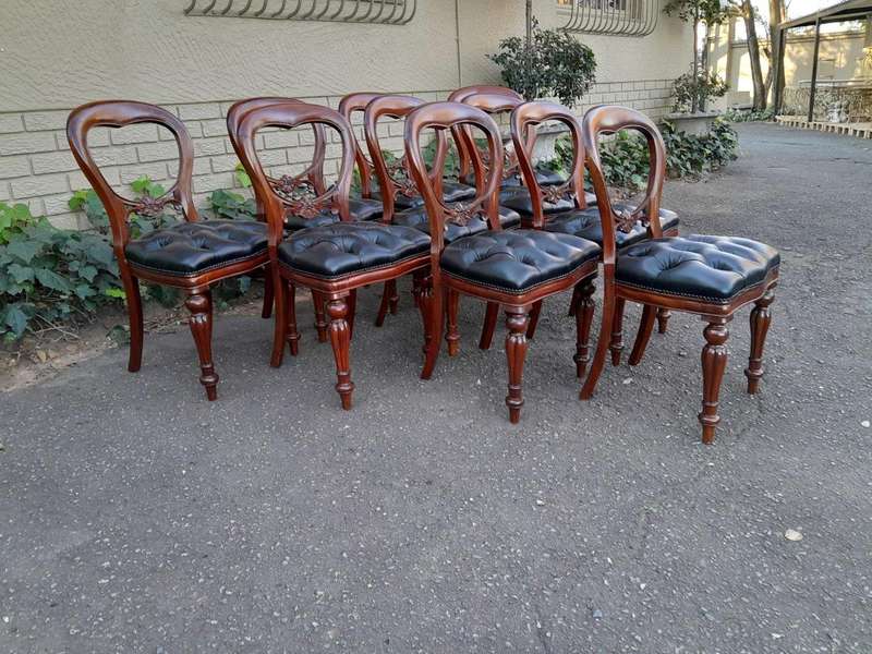 A 20th Century Set of Ten Teak Wood Bustle Back Chairs Upholstered in Deep Buttoned Leather