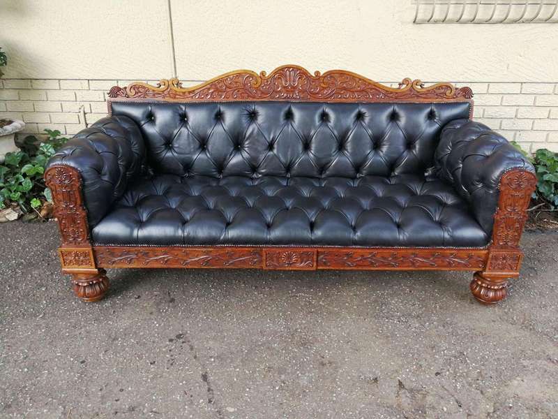 An Anglo Indian Carved Rosewood and Teak settee with brass castors