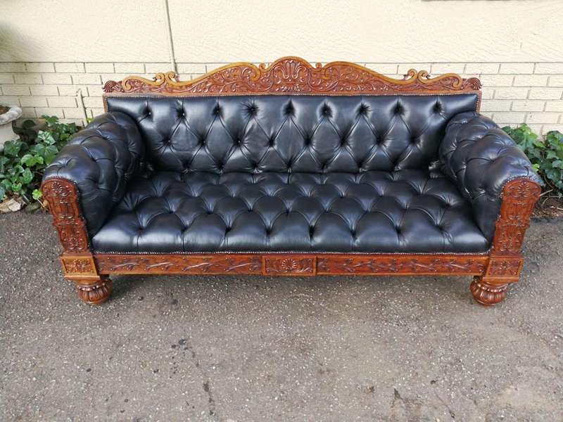 An Anglo Indian Carved Rosewood and Teak settee with brass castors
