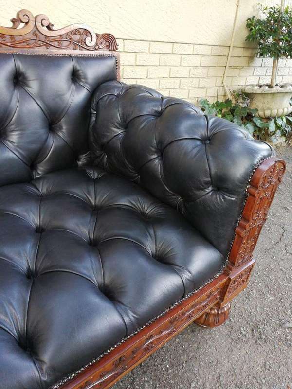An Anglo Indian Carved Rosewood and Teak settee with brass castors