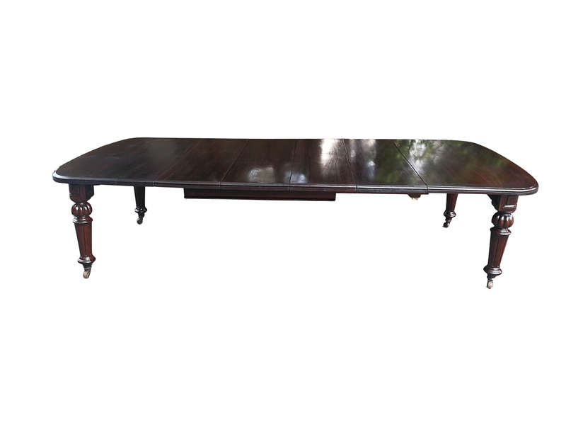 A three meter Victorian mahogany extending dining table on carved legs and castors, with four lea...