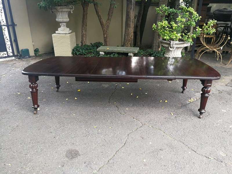 A three meter Victorian mahogany extending dining table on carved legs and castors, with four lea...