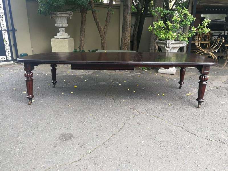A three meter Victorian mahogany extending dining table on carved legs and castors, with four lea...