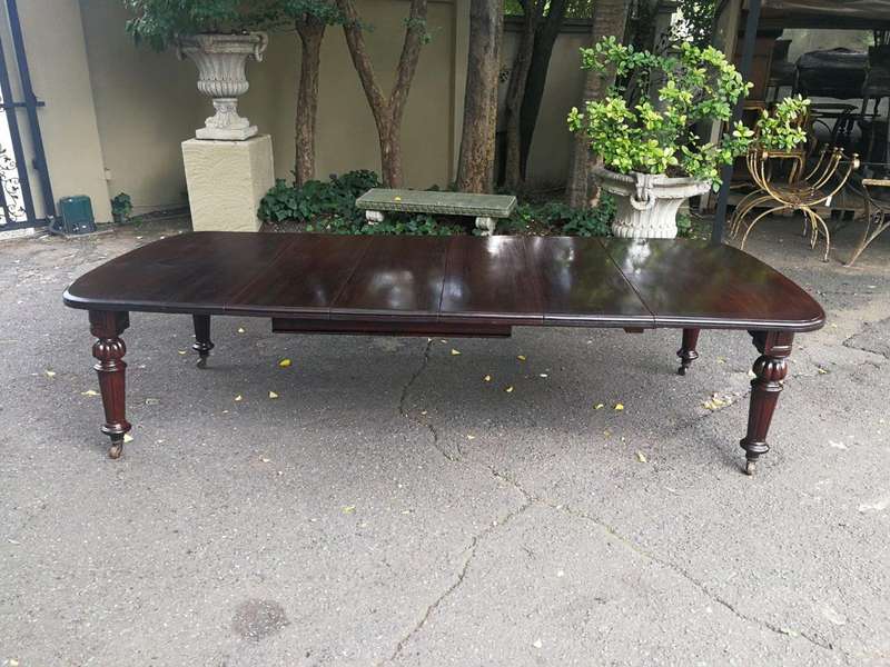 A three meter Victorian mahogany extending dining table on carved legs and castors, with four lea...