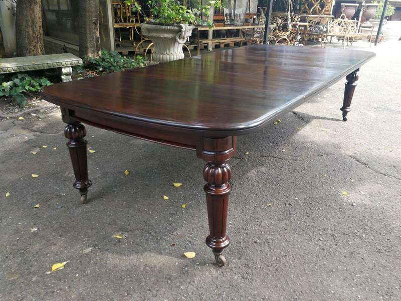 A three meter Victorian mahogany extending dining table on carved legs and castors, with four lea...