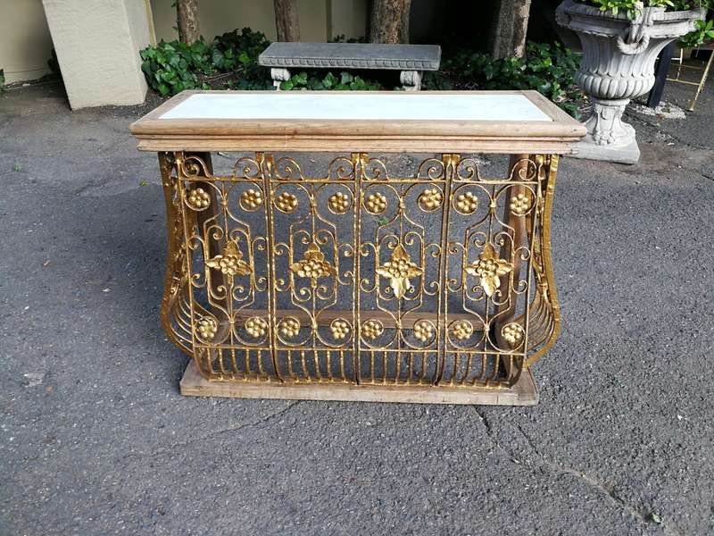 A wooden and marble-topped cast-iron console table