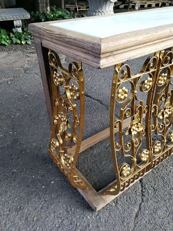 A wooden and marble-topped cast-iron console table