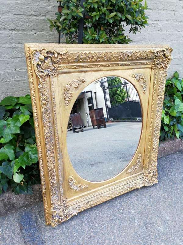 An Early 20th Century Gilded Oval Mirror Within A Rectangular Frame