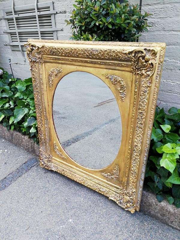 An Early 20th Century Gilded Oval Mirror Within A Rectangular Frame