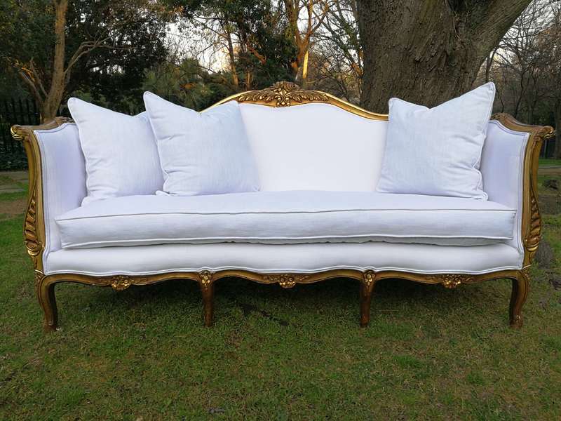 A French Louis XVl Style Gilded Settee Upholstered in a White Linen with Three Scatter Cushions
