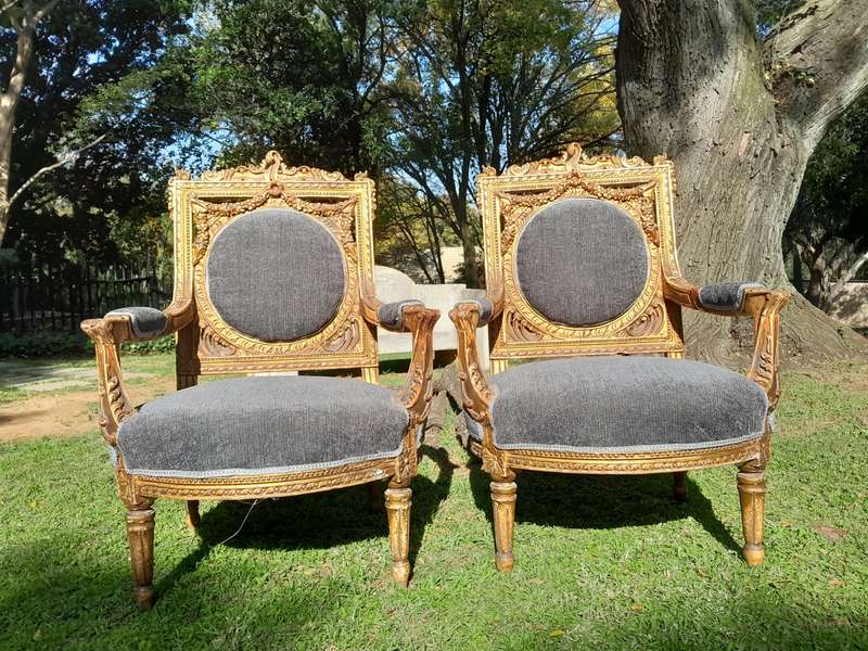 A 20th Century French Style Ornately Carved and Gilded Pair of Arm Chairs