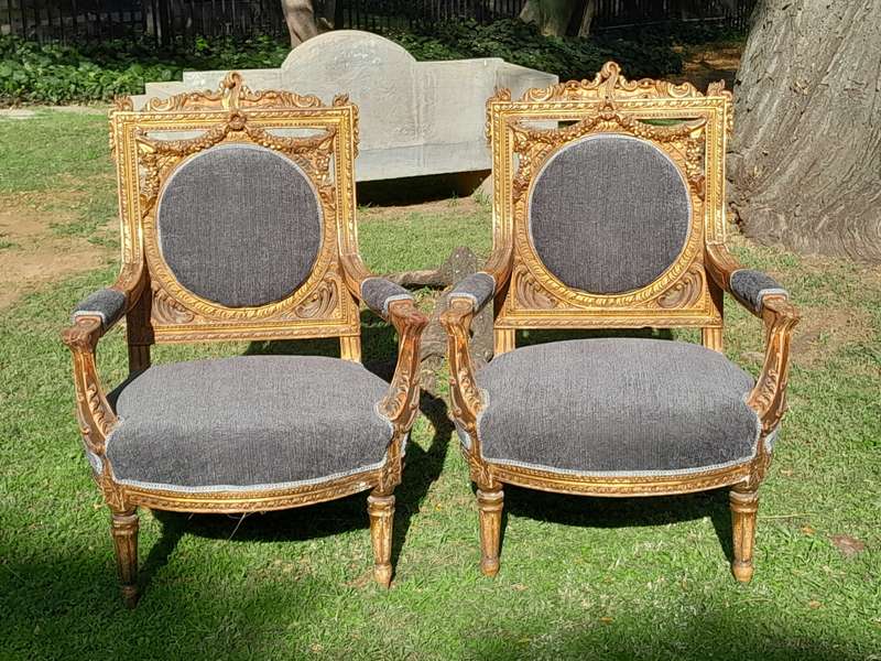 A 20th Century French Style Ornately Carved and Gilded Pair of Arm Chairs
