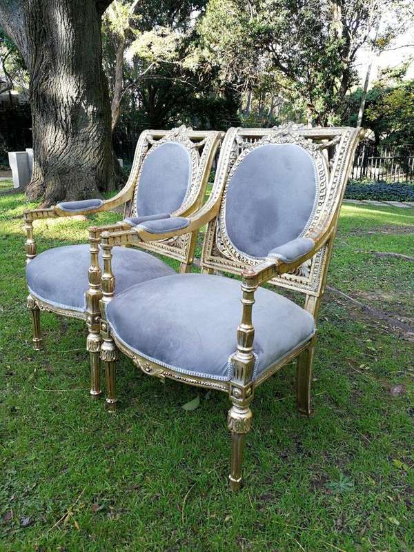 A 20th Century French Style Ornately Carved and Gilded Pair of Arm Chairs