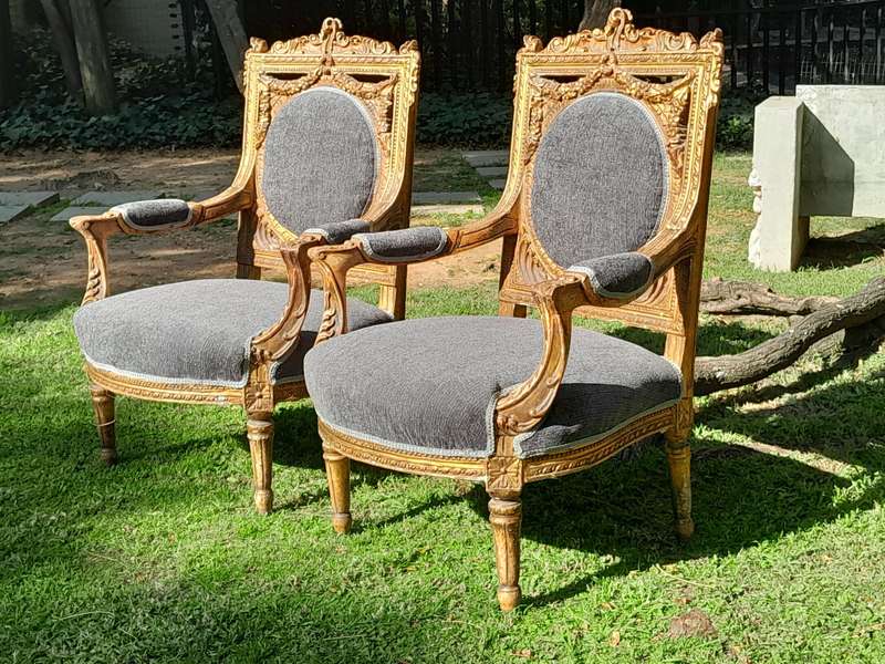A 20th Century French Style Ornately Carved and Gilded Pair of Arm Chairs