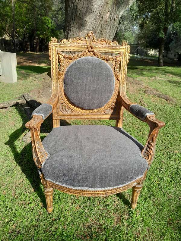 A 20th Century French Style Ornately Carved and Gilded Pair of Arm Chairs
