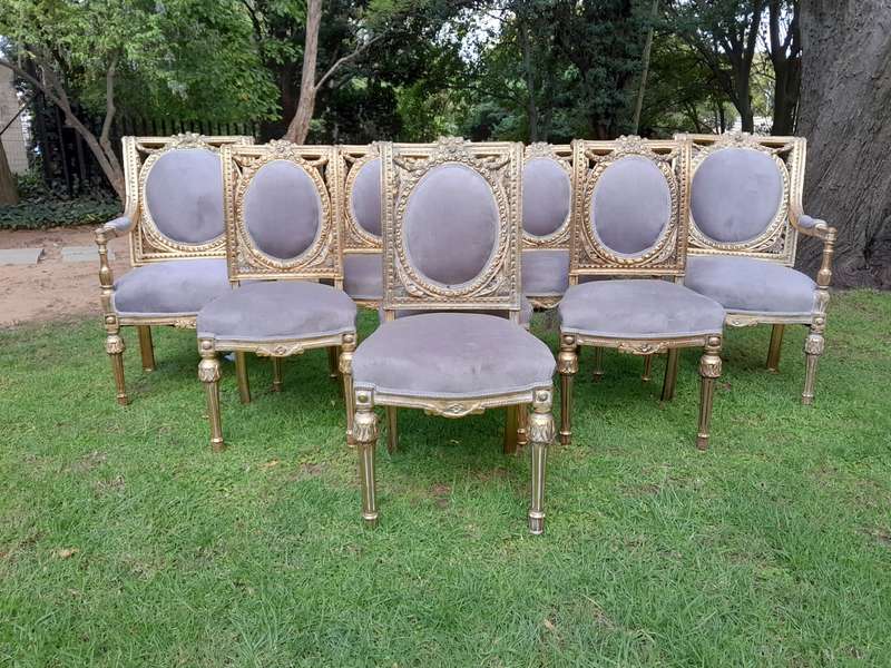 A Set of Eight French Style Ornately Carved and Gilded Dining Chairs (6 chairs and 2 Carvers)