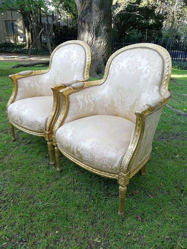 A Pair of French Louis XVI  Style Ornately Carved and Gilded Armchairs