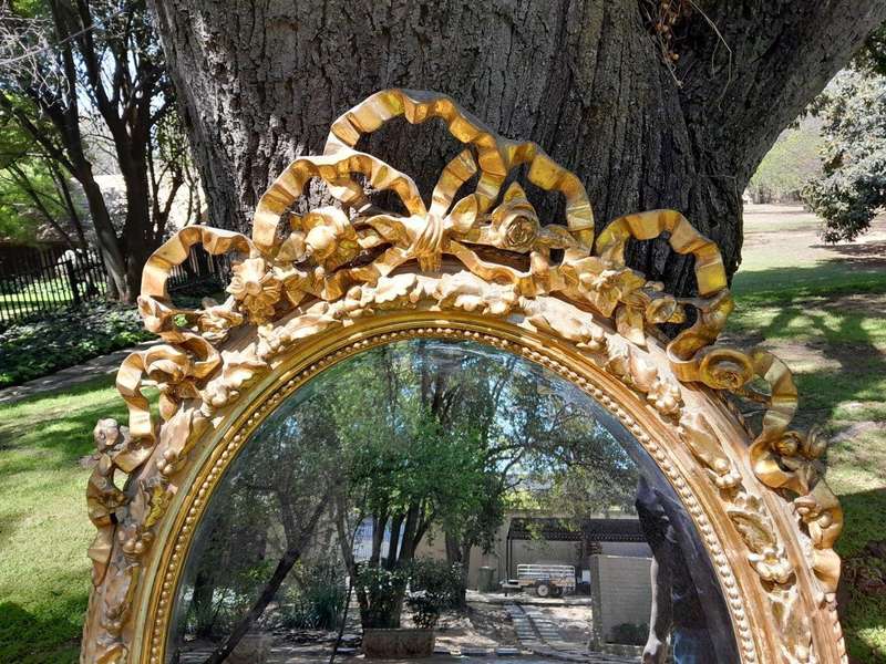 A French Rococo Style Ornately Carved and Gilded Oval Bevelled Mirror