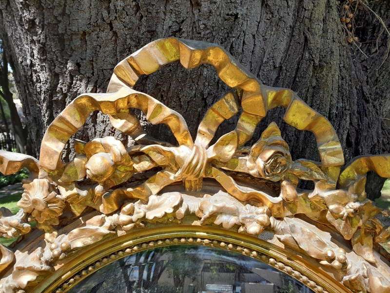 A French Rococo Style Ornately Carved and Gilded Oval Bevelled Mirror