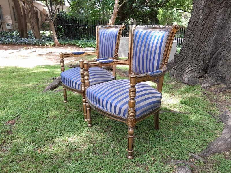 A Pair Of 20th Century French Louis XVI Styled Ornately Carved And Gilded Arm Chairs