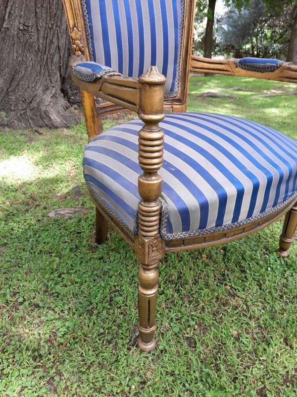 A Pair Of 20th Century French Louis XVI Styled Ornately Carved And Gilded Arm Chairs