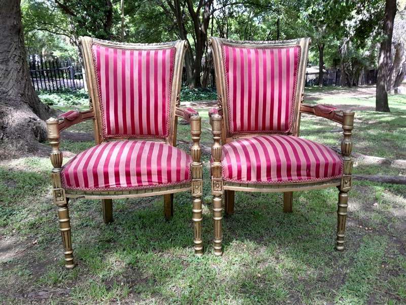 A Pair Of 20th Century French Louis XVI Styled Ornately Carved And Gilded Arm Chairs