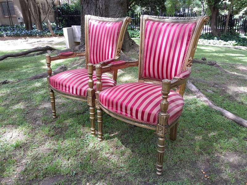 A Pair Of 20th Century French Louis XVI Styled Ornately Carved And Gilded Arm Chairs
