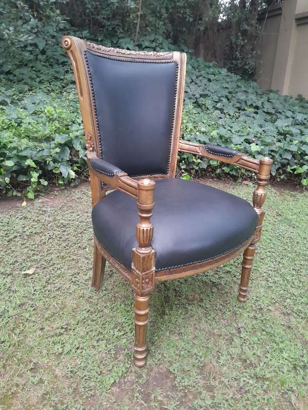 A 20th Century French Louis XVI Styled Ornately Carved And Gilded Arm Chair upholstered in black ...