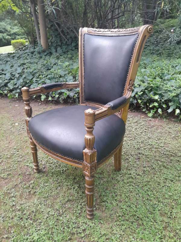 A 20th Century French Louis XVI Styled Ornately Carved And Gilded Arm Chair upholstered in black ...