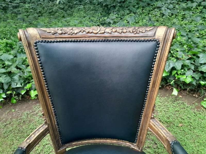 A 20th Century French Louis XVI Styled Ornately Carved And Gilded Arm Chair upholstered in black ...