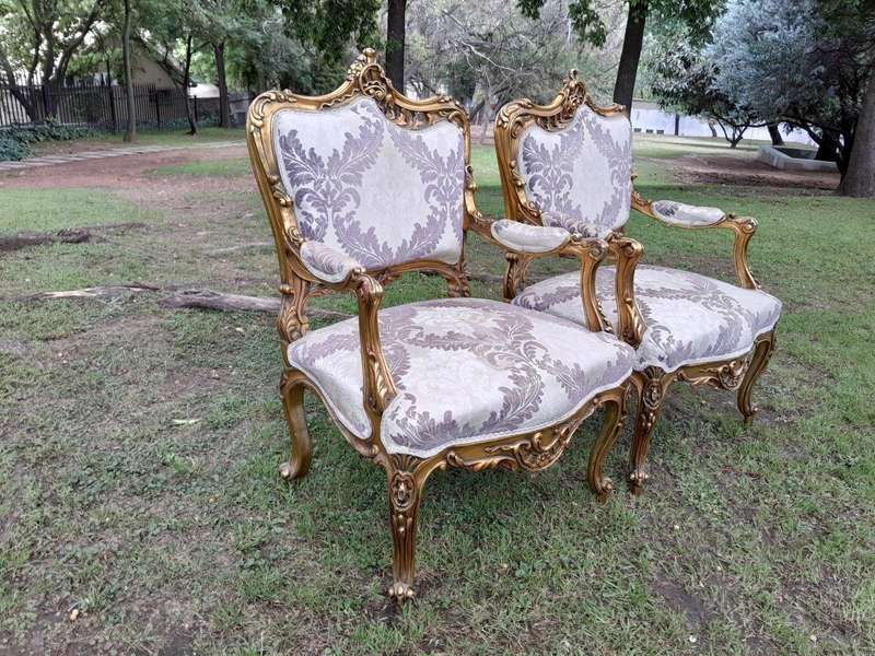 A 20th Century Pair Of French Rococo Style Ornately Carved Wooden Gilt-Wood Arm Chairs