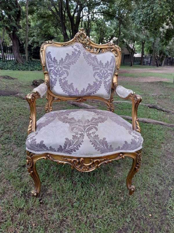 A 20th Century Pair Of French Rococo Style Ornately Carved Wooden Gilt-Wood Arm Chairs