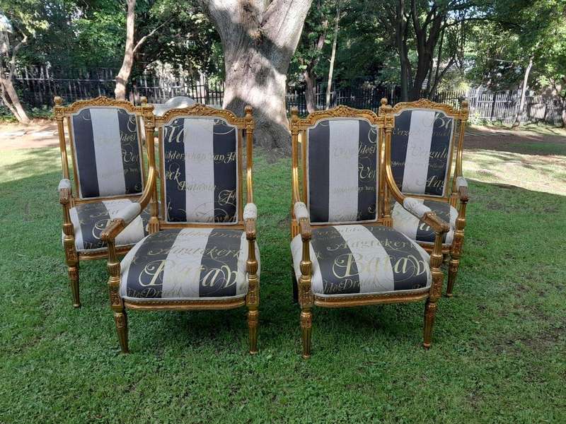 A French Style Set Of Four Ornately Carved And Gilded Armchairs In A Custom-Made Stripe And Scrip...