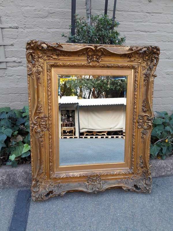 An Ornately Carved Gilt Framed Bevelled Mirror