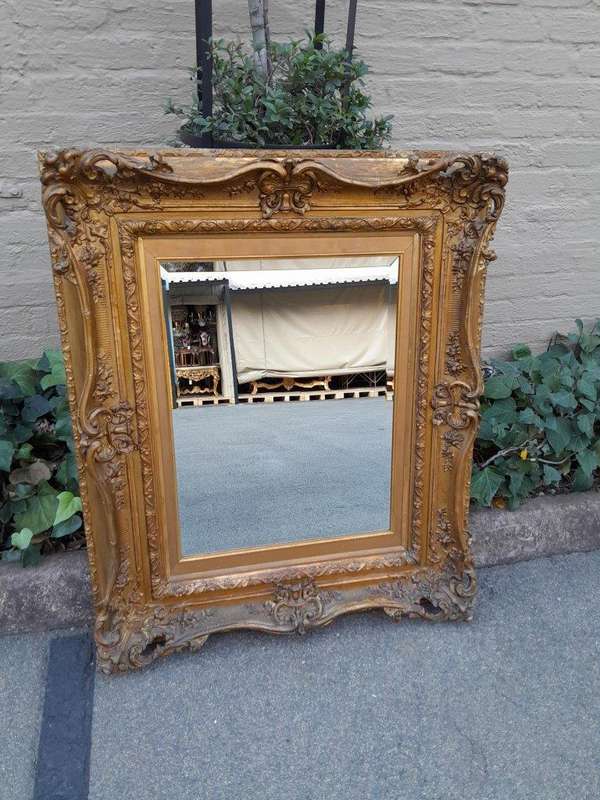 An Ornately Carved Gilt Framed Bevelled Mirror