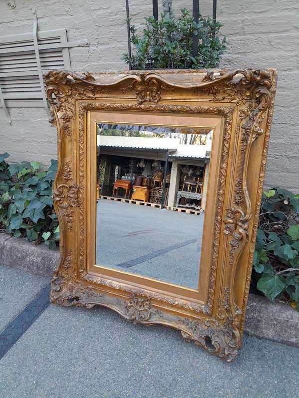 An Ornately Carved Gilt Framed Bevelled Mirror