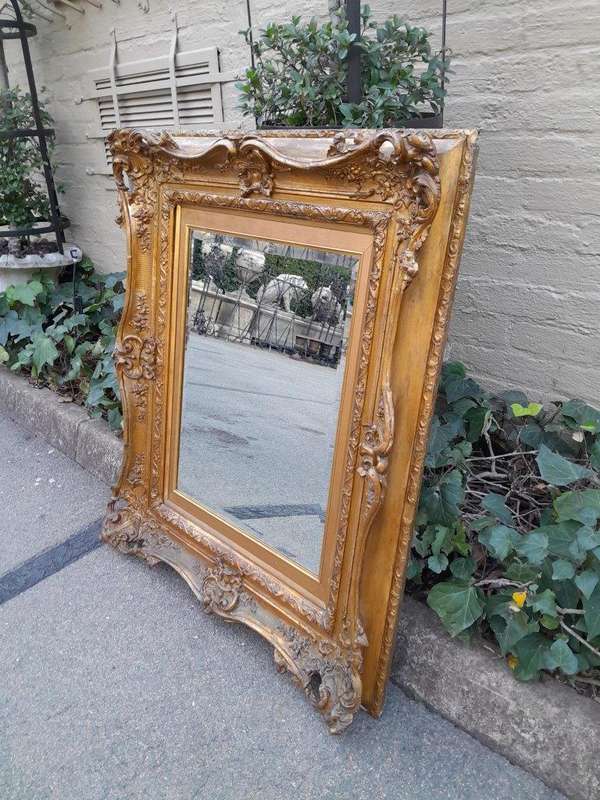 An Ornately Carved Gilt Framed Bevelled Mirror