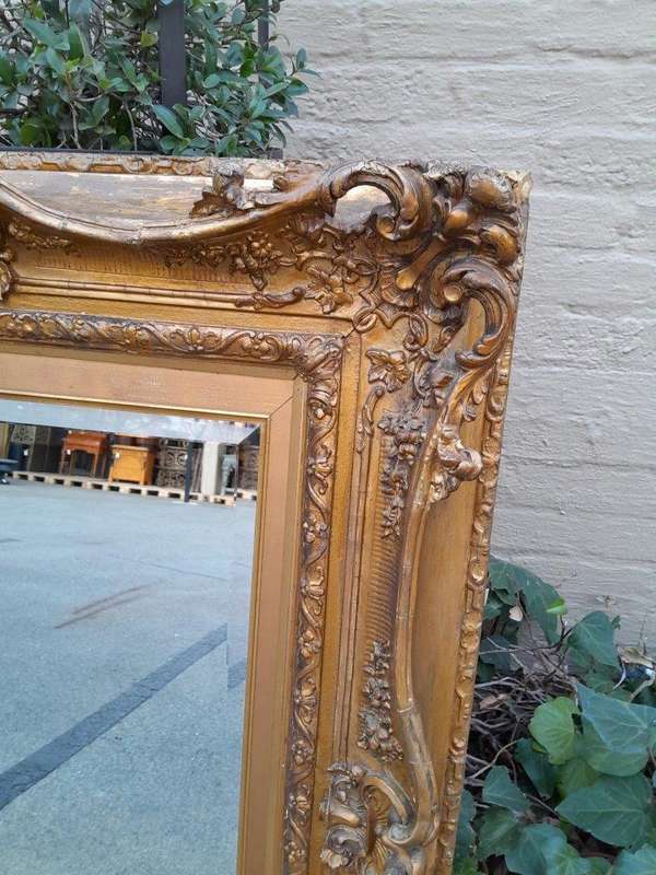 An Ornately Carved Gilt Framed Bevelled Mirror
