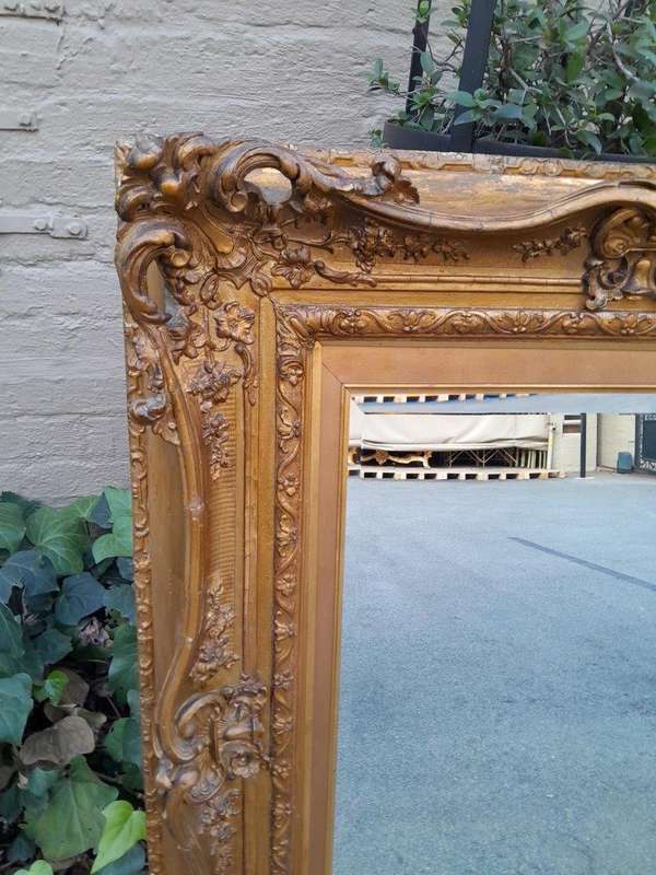 An Ornately Carved Gilt Framed Bevelled Mirror