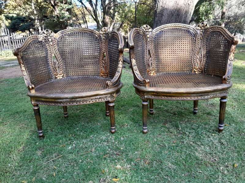 A French Louis XVI Style Pair of Ornately Carved Giltwood Rattan Bergere Chairs
